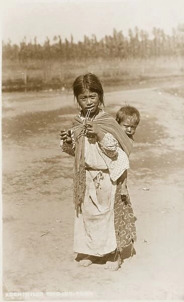 A Mexican girl carrying her younger brother