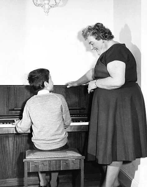 Mrs Mills, celebrity pianist, with boy at piano