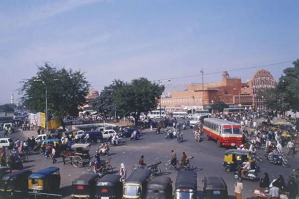 India, Jaipur, different modes of transport jostling streets, buses, rickshaws, cars, bicycles and pedestrians, grandiose facade of Hawa Mahal in background