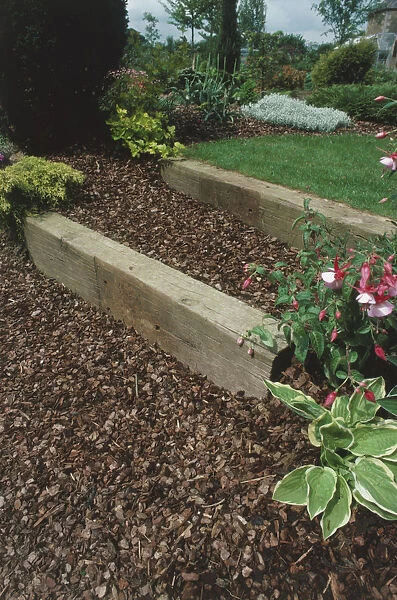 Using wooden railway sleepers for stepped borders in a garden to eliminate a slope