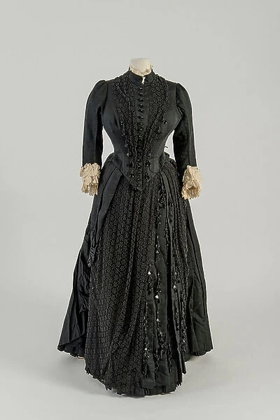 Black corded silk dress trimmed with an asymmetrical drapery of black net embroidered with small stars in black beads and jet tassels, 1880s (silk, net & beads)