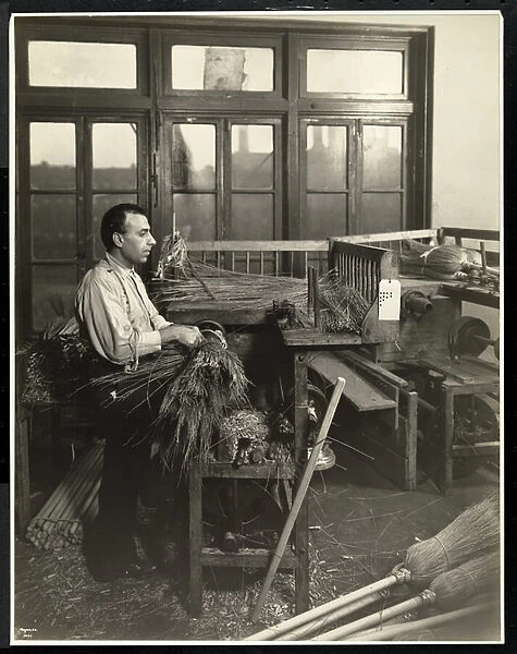 Blind man fastening straw on broom handles at the Bourne Memorial Building, New York