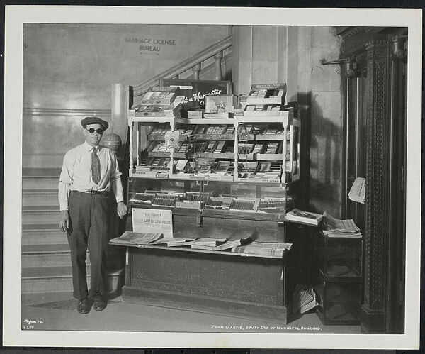 Blind news dealer, John Martie, at his stand at the south end of the Municipal Building