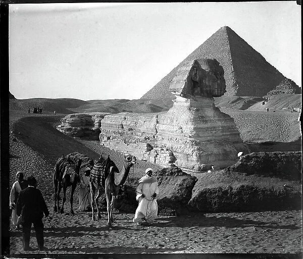 Egypt, Cairo: Cook cruise, the pyramid of Kheops (Cheops, Keops, Khufu, Khufu) to Guizeh (Guiseh, Giza, Giza) and the sphinx, tourists pose at the level of the undegagee legs of the sphinx - Guides and their camels, 1900