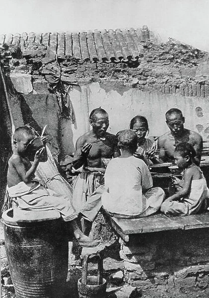 The family meal in a house partially destroyed during the siege of Tientsin, 1900 (b / w photo)