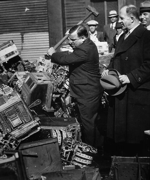 Fiorello La Guardia (1882-1947) smashing confiscated slot machines, 1934 (b  /  w photo)