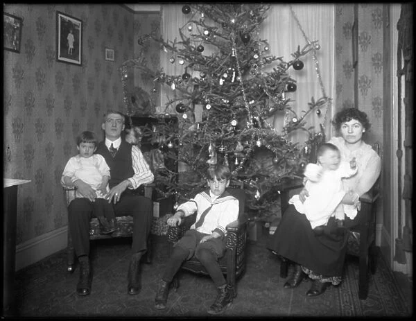 Informal group portrait of unidentified family in their apartment seated in front of a