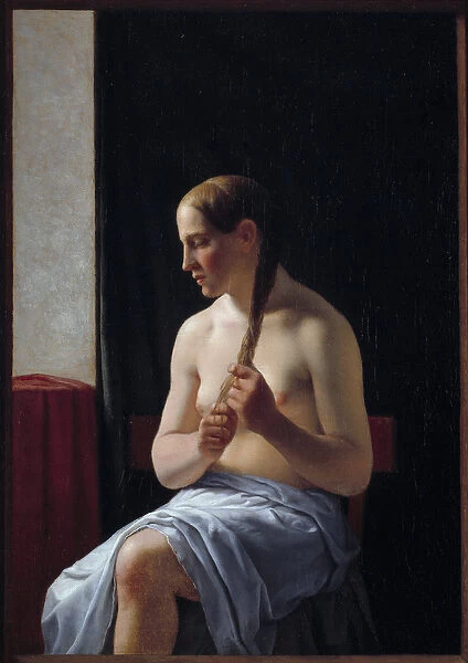 Nude model sitting. Portrait of a woman braiding her hair (braid)