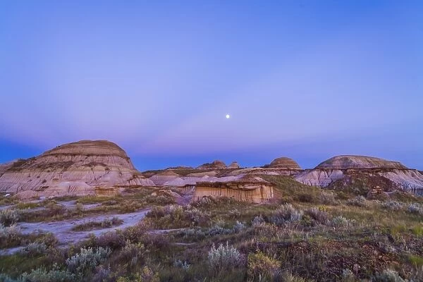 Gibbous moon and crepuscular rays over Dinosaur Provincial Park, Canada