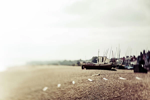 A traditional fishing boat on the shore with mist along the coast