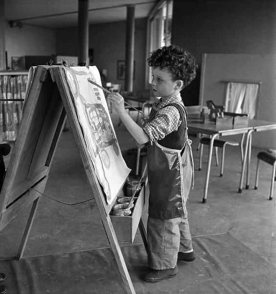 Young boy standing by his easel during an art class at Cookham Nursery School