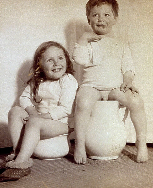 Portrait of two semi-nude children seated on potties
