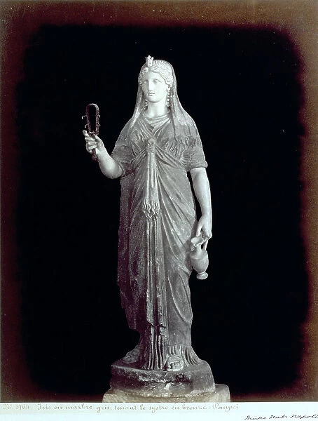 Roman statue of Isis. The goddess, dressed in classic attire, holds a sistrum in her right hand, and a pitcher in her left