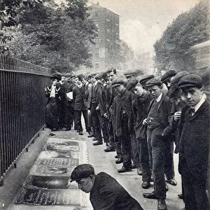 Crowd of flat capped youths watching a street artist