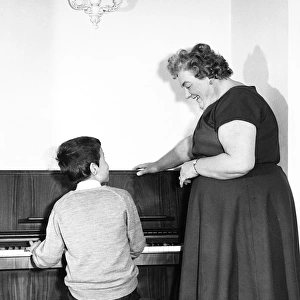 Mrs Mills, celebrity pianist, with boy at piano