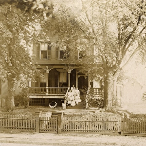 Women and children posing on front steps of house, USA