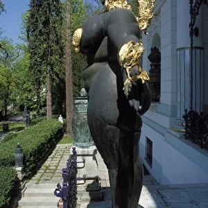 Close-up, side view of a female nude statuewith gold headdress in front of the building