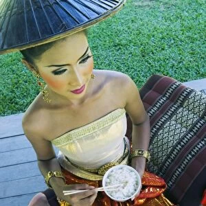 Girl in traditional Thai clothes eating rice