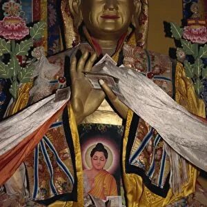 Statue with scarves and offerings of money in Ganden monastery, Tibet, China, Asia