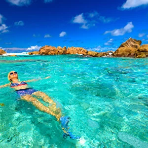 Swimming pool at Anse Cocos with woman in bikini lying in turquoise water of natural