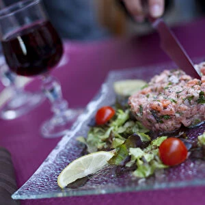 A diner cutting into steak tartare in a restaurant in paris France