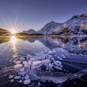 Ice bubbles trapped in the frozen Lake Sils, during a sunsetcanton of Graubunden, Engadine, Switzerland