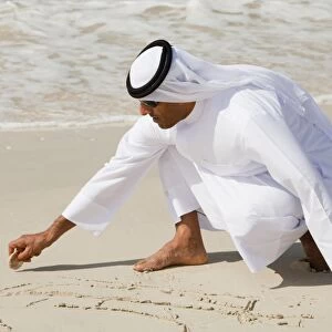 An arab man wearing traditiional dress on a beach in Dubai