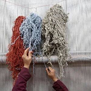 An Afghan woman reaches for a thread while working at the Afghanistan Rug