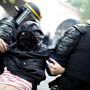 French riot police apprehend a masked and hooded protester after clashes at a