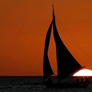 Tourists ride on a sailboat during sunset at Boracay