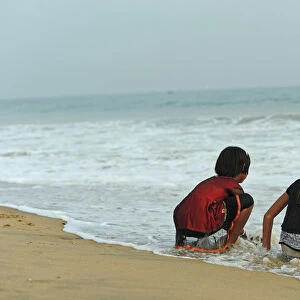 India, Odisha, Puri, two girl friends having fun with the waves of the ocean