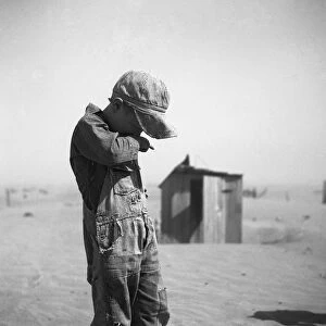 DUST BOWL, 1936. A farmers young son covering his mouth during a dust storm in Cimarron County