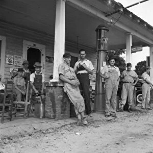 FOURTH OF JULY, 1939. A group of men hanging out at a small fuel filling station