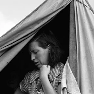 MIGRANT CAMP, 1939. A woman in the doorway of a tent at a camp for migrant workers