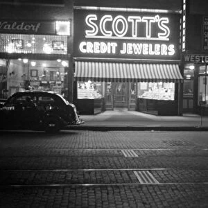 STOREFRONT, c1937. Illuminated signs and storefronts on a street, possibly in New Hampshire