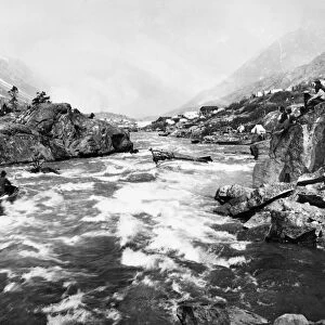 YUKON RIVER RAPIDS, 1898. A group of miners watching two men braving the rapids of