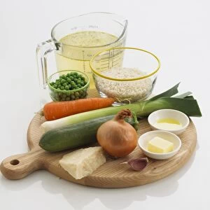Ingredients for making a risotto, including risotto rice, stock, peas, carrots, leek, courgette, onion, parmesan cheese, garlic, butter, olive oil