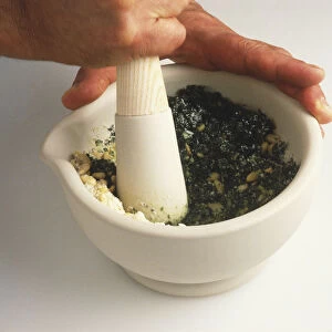 Person mixing pesto in a pestle and mortar