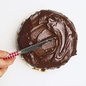 Spreading chocolate onto a cake with a knife, view from above