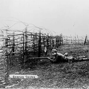 World War I 1914-1918: German sniper wearing a pickelhelm, lying on the ground behind