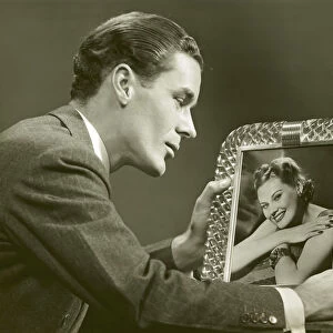 Man gazing at framed photo of woman