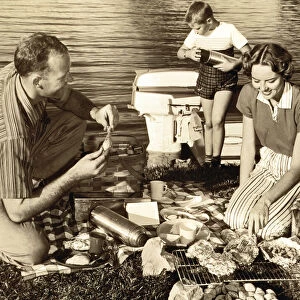 Parents and son (11-13) having barbecue by lake (B&W sepia tone)