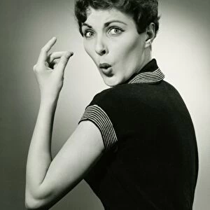 Woman whistling and snapping fingers in studio, (B&W), portrait