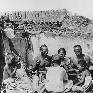 The family meal in a house partially destroyed during the siege of Tientsin, 1900 (b/w photo)