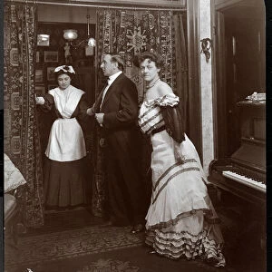A formally dressed man and woman and what appears to be a domestic servant in a room with