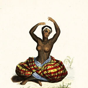Tattooed and bare-breasted young woman dancing a hula while seated on the ground