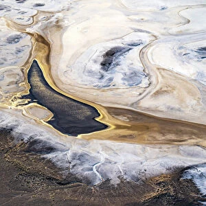 Aerial view after sunrise, showing the sun reflecting off water that has flowed into Lake Eyre South and formed a pond; the water being the result of recent uncommonly high local desert rainfall