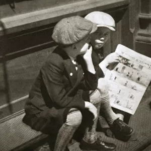 Two boys reading the comic section of the Sunday paper, New York, USA, 1931. Artist