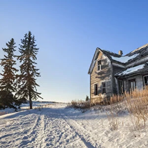Dilapidated farm house at sunrise in winter