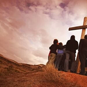 A Group Of People Standing At The Base Of A Large Wooden Cross
